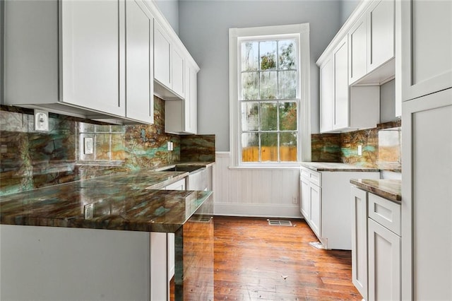 kitchen featuring white cabinets, dark stone counters, and light hardwood / wood-style floors