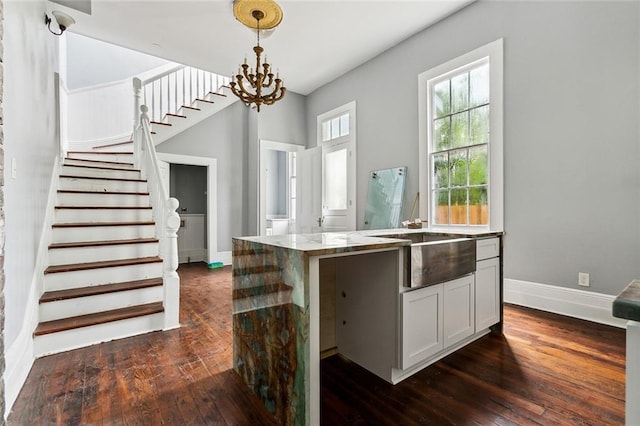 kitchen featuring a chandelier, light stone countertops, dark hardwood / wood-style floors, white cabinetry, and decorative light fixtures