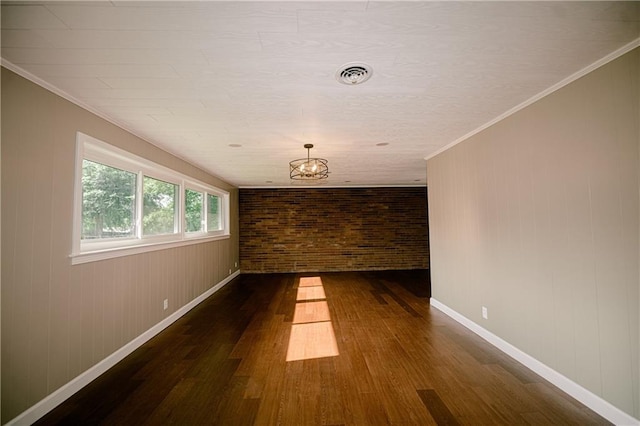 empty room featuring brick wall, crown molding, and dark hardwood / wood-style flooring