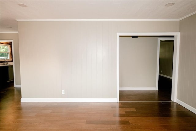 spare room featuring sink, dark wood-type flooring, and crown molding