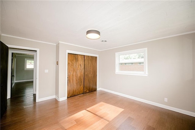 unfurnished bedroom featuring ornamental molding, a closet, and wood-type flooring