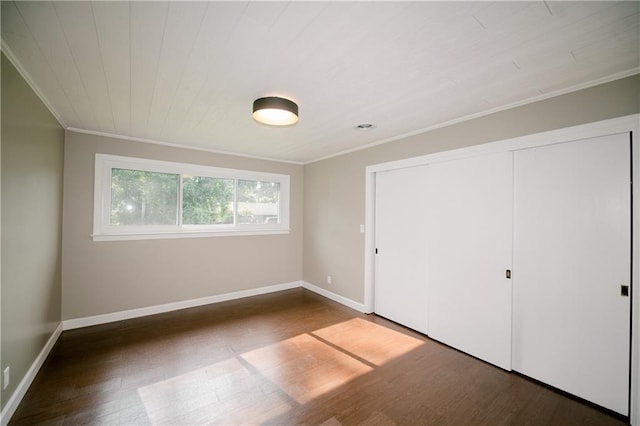 unfurnished bedroom with dark wood-type flooring, a closet, and crown molding