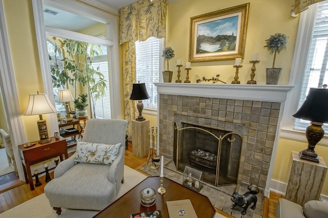 sitting room featuring a brick fireplace, a wealth of natural light, and wood-type flooring