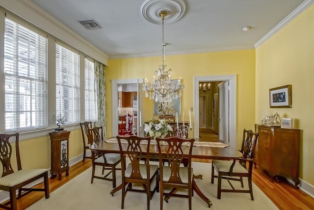 dining room with a notable chandelier, light hardwood / wood-style flooring, and ornamental molding