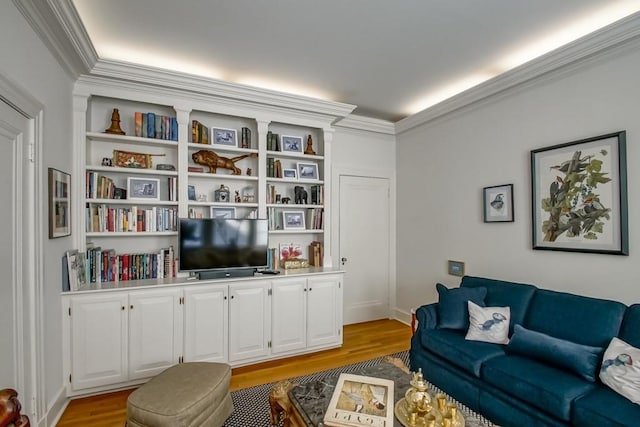 living room with light wood-type flooring, crown molding, and built in features