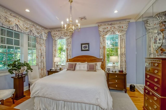 bedroom featuring a chandelier, multiple windows, light hardwood / wood-style floors, and crown molding