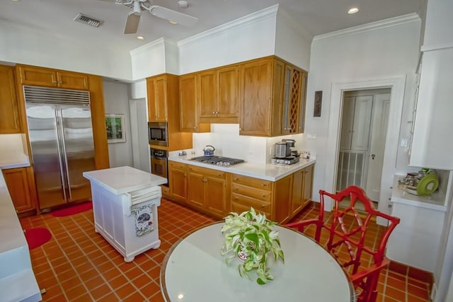 kitchen with built in appliances, ceiling fan, a kitchen island, and ornamental molding