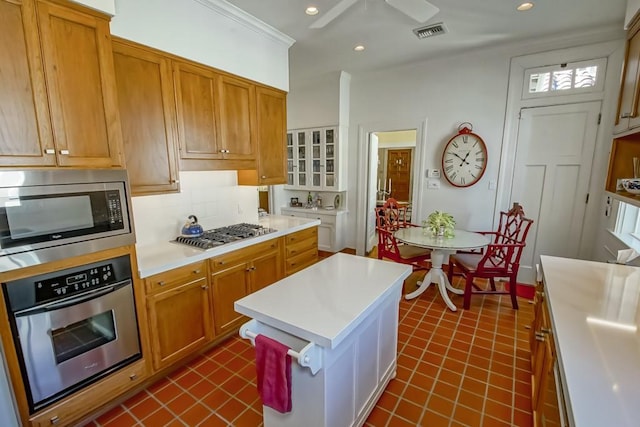 kitchen featuring appliances with stainless steel finishes, ornamental molding, backsplash, and a center island