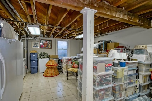 basement with white fridge and light tile patterned floors