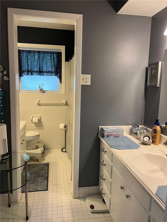 bathroom with toilet, tile patterned flooring, and vanity