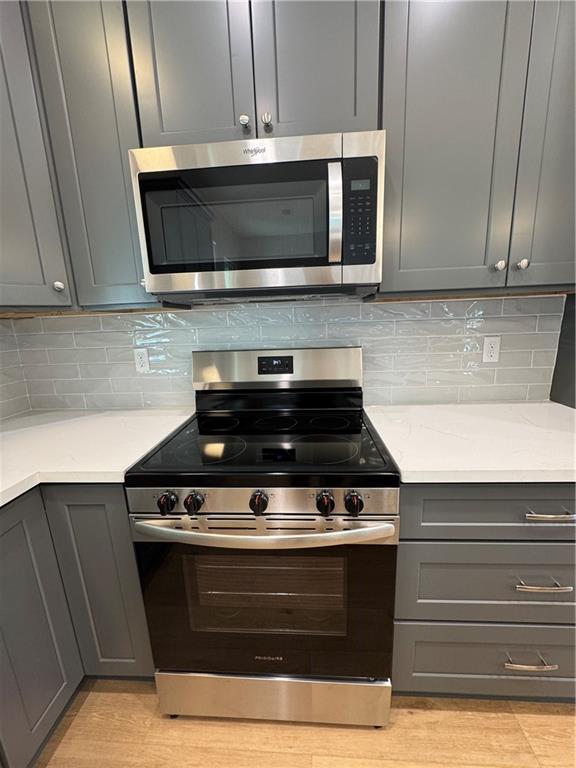 kitchen featuring appliances with stainless steel finishes, backsplash, and gray cabinets