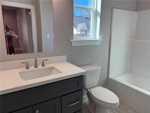 full bathroom featuring washtub / shower combination, vanity, and toilet