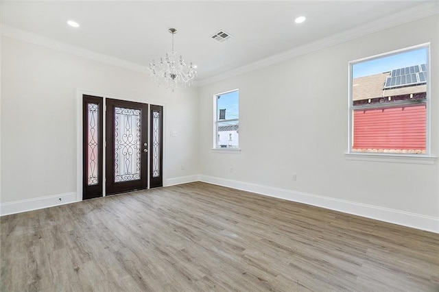 foyer featuring ornamental molding, an inviting chandelier, a wealth of natural light, and wood-type flooring