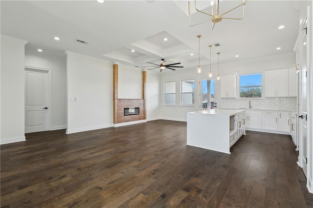 kitchen with white cabinetry, a center island, hanging light fixtures, dark hardwood / wood-style floors, and a tile fireplace