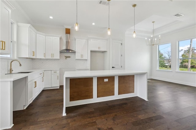 kitchen featuring white cabinetry, sink, a kitchen island, and wall chimney range hood