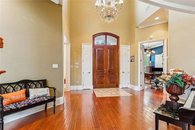 entrance foyer featuring a towering ceiling, hardwood / wood-style floors, and a notable chandelier