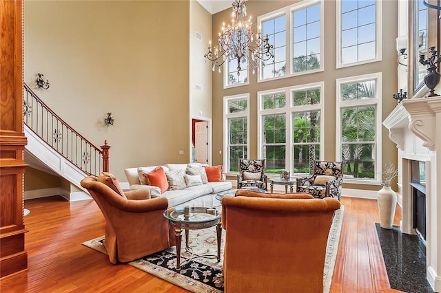 living room featuring a towering ceiling, a premium fireplace, and light wood-type flooring