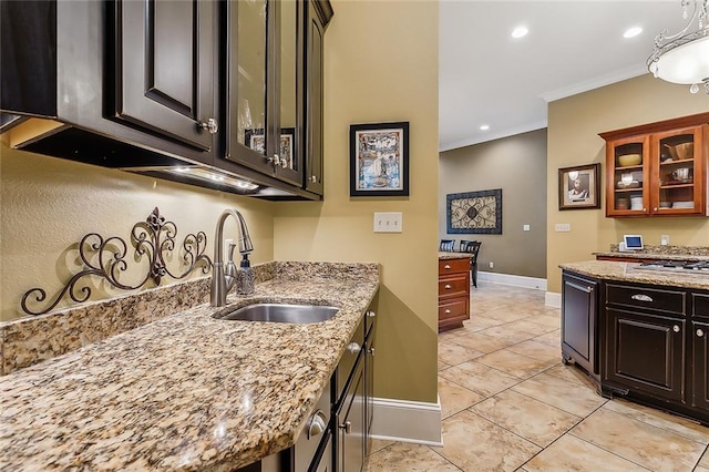 kitchen featuring light stone countertops, ornamental molding, dark brown cabinets, and sink