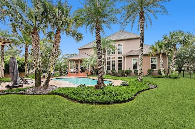 back of property with a fenced in pool, a patio area, and a lawn