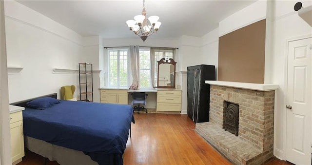 bedroom featuring a chandelier, built in desk, a fireplace, and wood finished floors