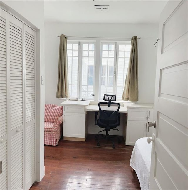 office space with dark wood-type flooring, built in study area, and visible vents