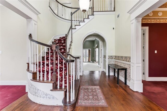 foyer featuring a towering ceiling, crown molding, and dark hardwood / wood-style floors