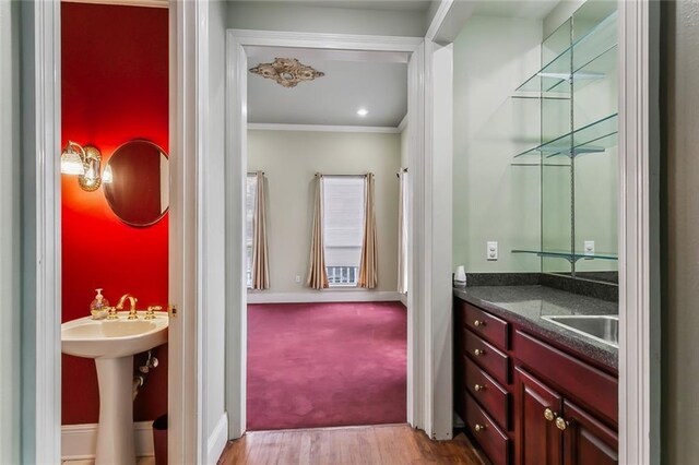 bathroom featuring crown molding, wood-type flooring, and sink