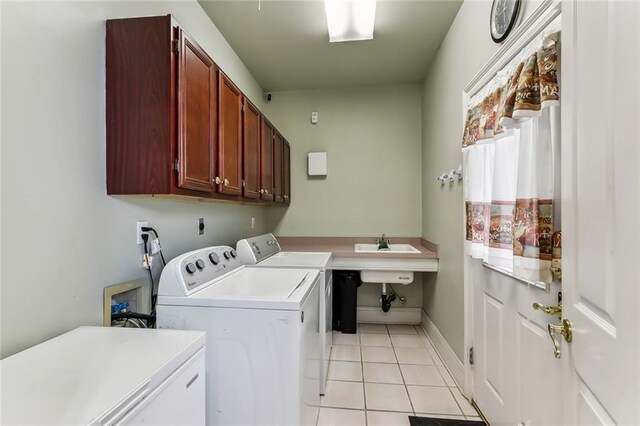 clothes washing area with washer and dryer, light tile patterned floors, and cabinets