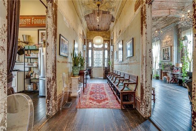 hall with dark hardwood / wood-style flooring, brick ceiling, and a towering ceiling