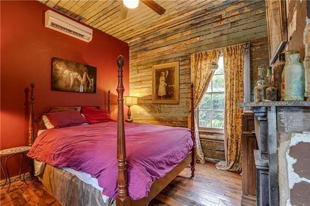 bedroom featuring wood-type flooring, wood ceiling, ceiling fan, and a wall mounted air conditioner