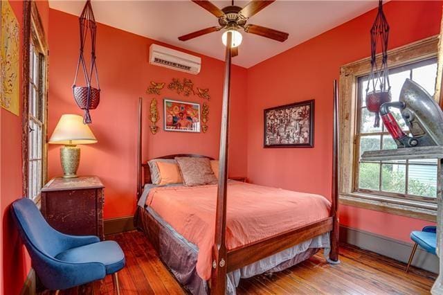 bedroom with ceiling fan, hardwood / wood-style flooring, and a wall mounted AC