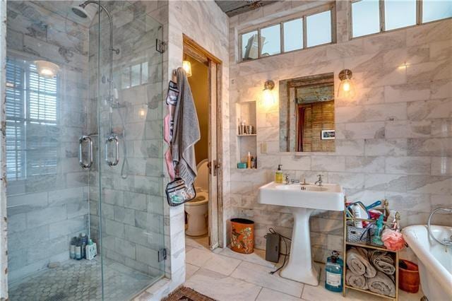 bathroom featuring tile walls, a shower with shower door, and toilet