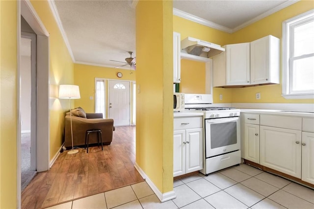 kitchen featuring white appliances, white cabinets, light tile patterned flooring, and ornamental molding