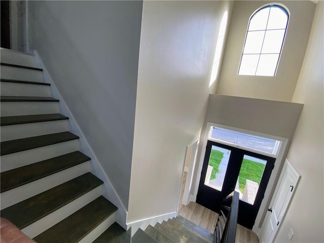 entryway with a wealth of natural light, stairs, a high ceiling, and wood finished floors