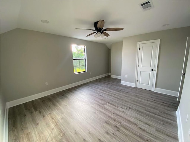 unfurnished bedroom featuring wood finished floors, baseboards, visible vents, and lofted ceiling