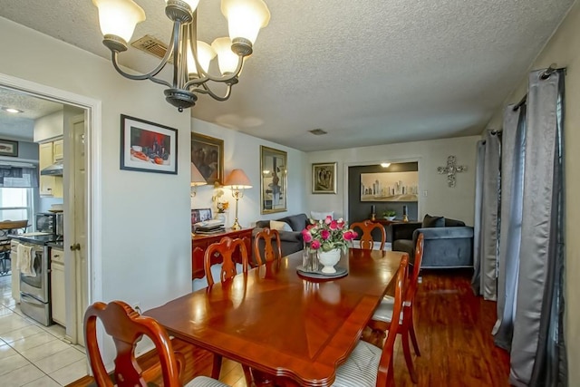 tiled dining area with a textured ceiling and a notable chandelier