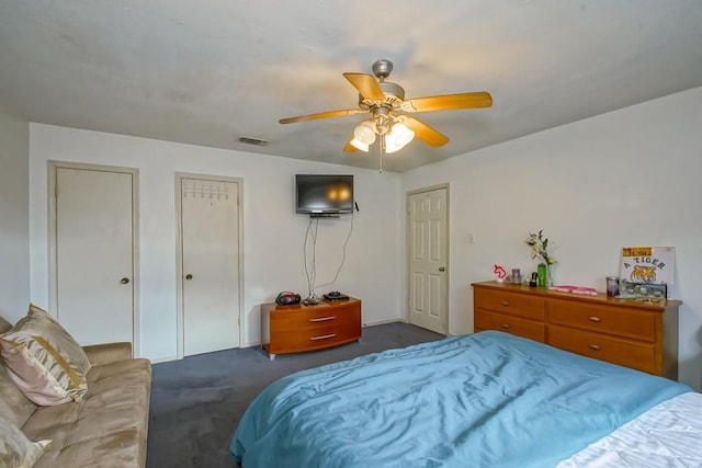 bedroom featuring two closets, ceiling fan, and dark carpet