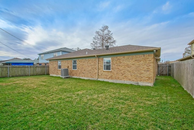 rear view of house featuring central air condition unit and a lawn