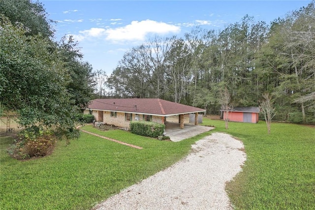 ranch-style home with a storage unit, a front lawn, and a carport