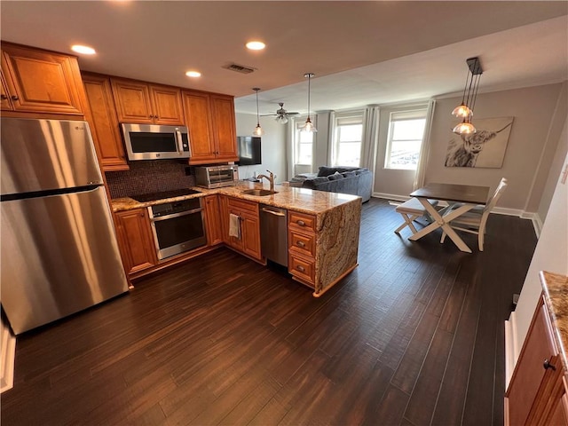 kitchen with decorative light fixtures, kitchen peninsula, sink, and stainless steel appliances