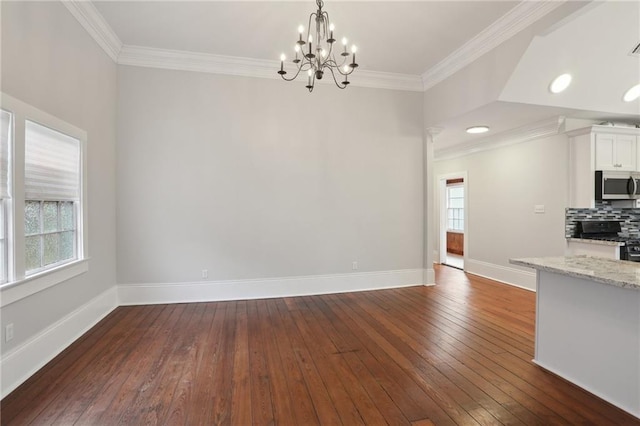 unfurnished dining area with ornamental molding, plenty of natural light, dark wood-type flooring, and a notable chandelier