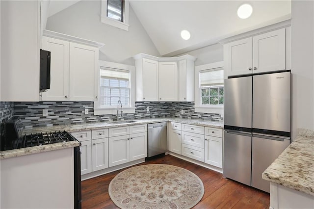 kitchen featuring sink, vaulted ceiling, appliances with stainless steel finishes, white cabinets, and backsplash