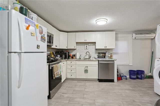 kitchen with sink, white cabinetry, light stone counters, appliances with stainless steel finishes, and backsplash