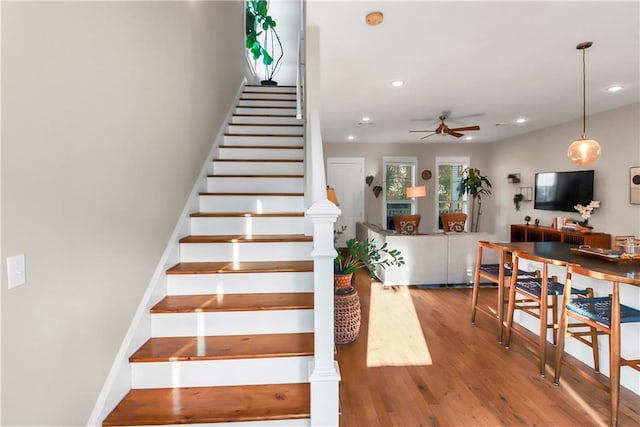 stairway with hardwood / wood-style floors and ceiling fan