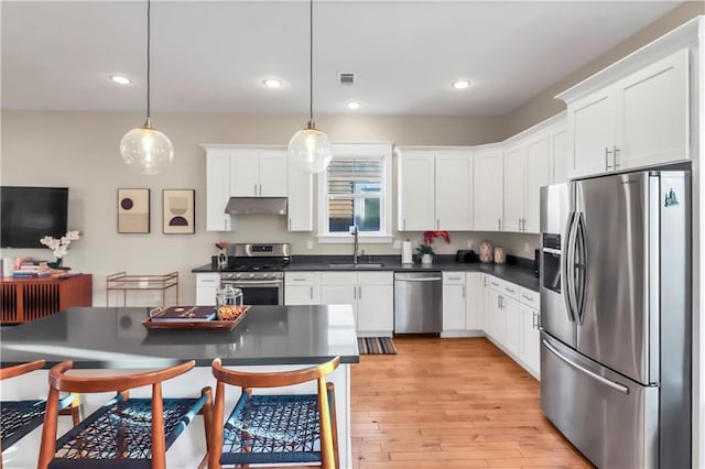 kitchen with appliances with stainless steel finishes, sink, hanging light fixtures, and white cabinets