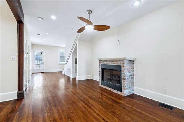 unfurnished living room featuring lofted ceiling, a fireplace, dark wood-type flooring, and ceiling fan