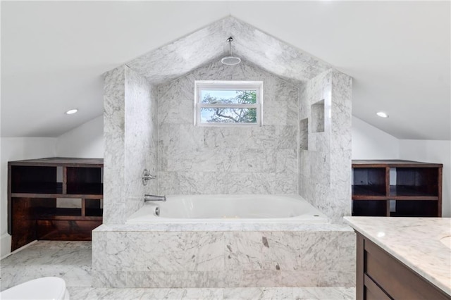 bathroom with lofted ceiling, tiled tub, and vanity