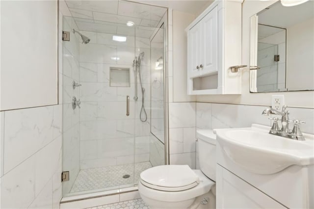 bathroom with toilet, vanity, tile walls, and a shower with shower door