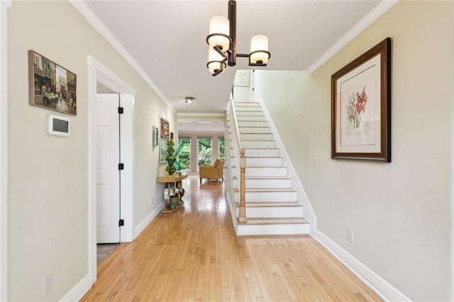 interior space featuring light wood-type flooring, ornamental molding, and a notable chandelier