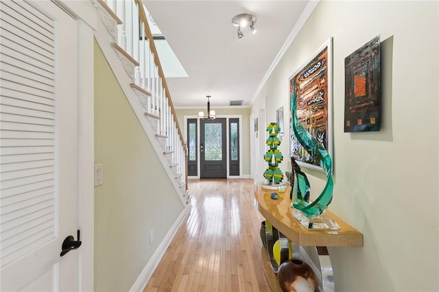 foyer entrance with crown molding, a chandelier, and light hardwood / wood-style floors